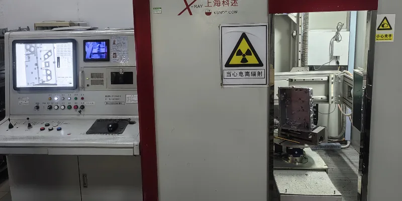 A technician operating an industrial X-ray machine with an aluminum casting inside for internal defect analysis.