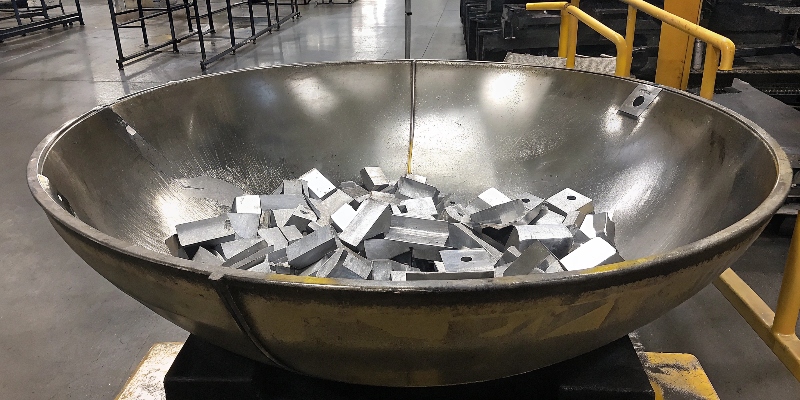 A large vibratory finishing bowl filled with aluminum parts and ceramic abrasive media.