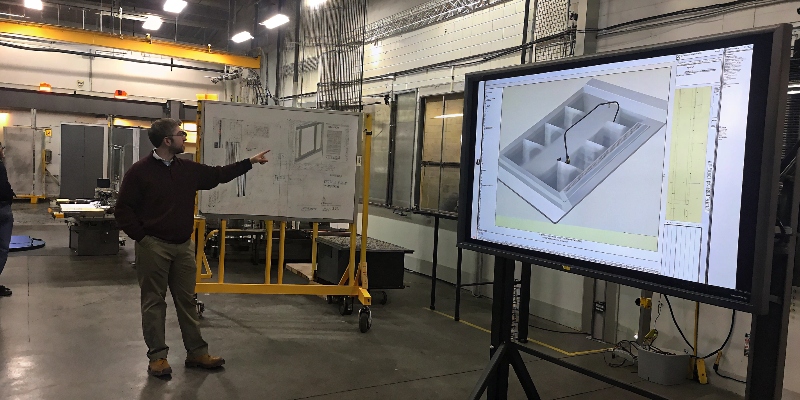 An engineer pointing out design features on a 3D CAD model during a DFM review