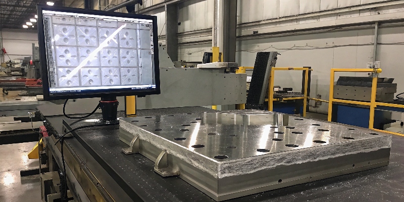 Aseguramiento de la Calidad IATF 16949 Un ingeniero de calidad inspeccionando una pieza de aluminio con una máquina de medición por coordenadas (CMM) de alta precisión