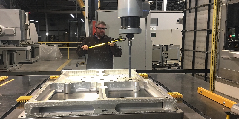 Un ingeniero de calidad inspeccionando una pieza de fundición de aluminio con una máquina de medición por coordenadas (CMM)