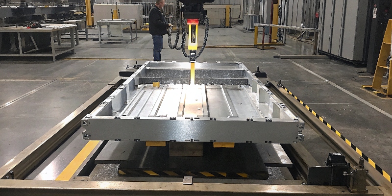 Un inspector de calidad utilizando un CMM para medir una pieza de fundición de aluminio en un entorno de producción limpio