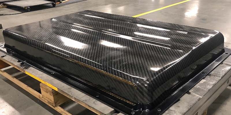 Una tapa de fibra de carbono para un paquete de baterías, destacando su ligereza y acabado