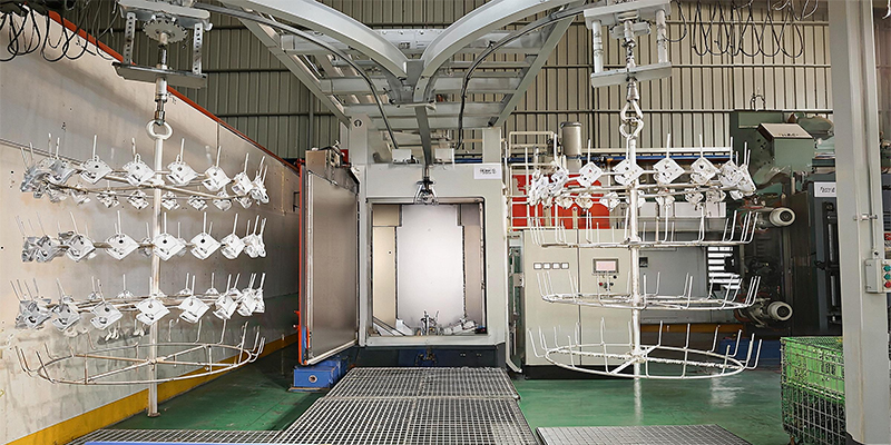 Applying Post-Casting Treatments and Repairs An industrial vacuum impregnation chamber with a basket of aluminum parts being lowered into it.