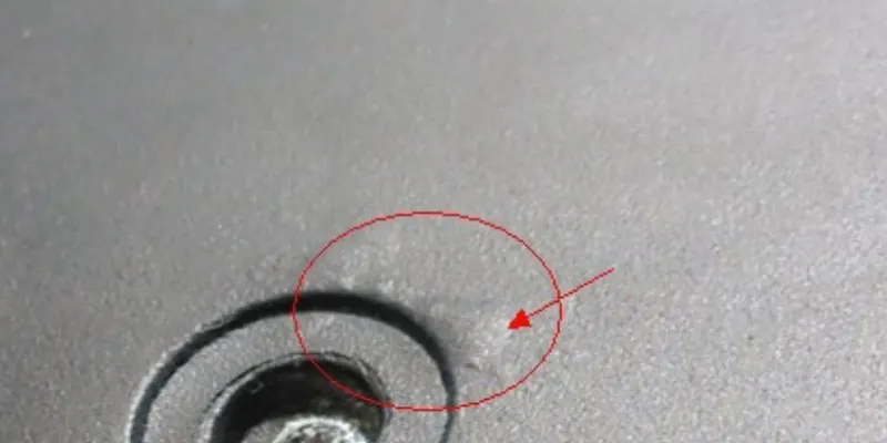 A die cast component showing a noticeable sunken depression (shrinkage) on a thick section, and another part next to it with a raised blister on the surface.