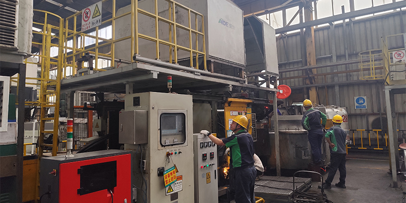 A die-casting machine operator reviewing a screen showing real-time data graphs of injection pressure, speed, and temperature.