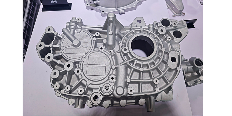A detailed cutaway of an EV chassis, highlighting the large, single-piece aluminum die-cast battery enclosure and motor housing.