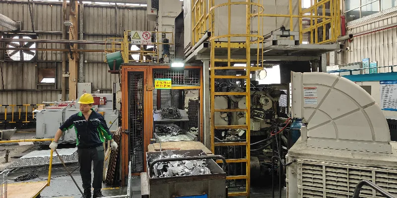 Robotic arm extracting a die-cast automotive transmission housing A dynamic shot of a robotic arm pulling a complex, newly formed aluminum transmission housing from a die casting machine.
