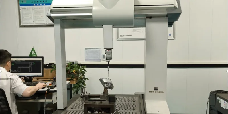 An inspector using a Coordinate Measuring Machine (CMM) to verify the tight tolerances of a CNC-machined automotive component, showing a screen with green "pass" indicators.