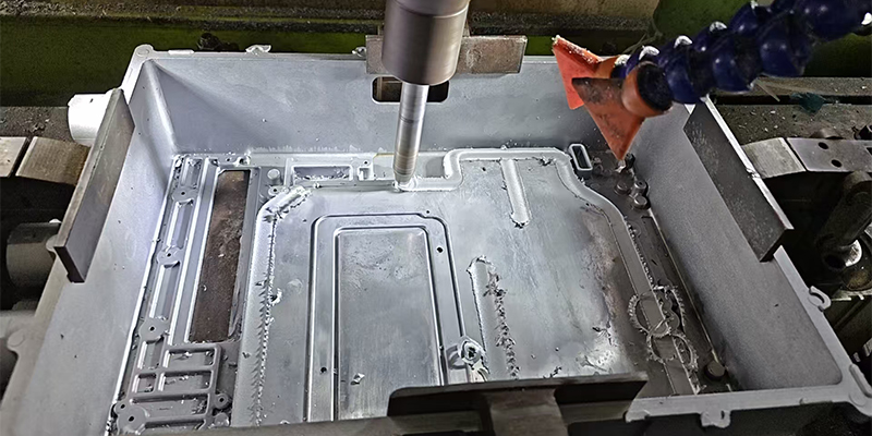 A close-up shot of a friction welding machine in action, with a glowing red-hot interface between two metal parts.
