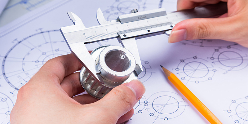 A digital caliper measuring a critical dimension on a complex aluminum die-cast part to within micrometers.