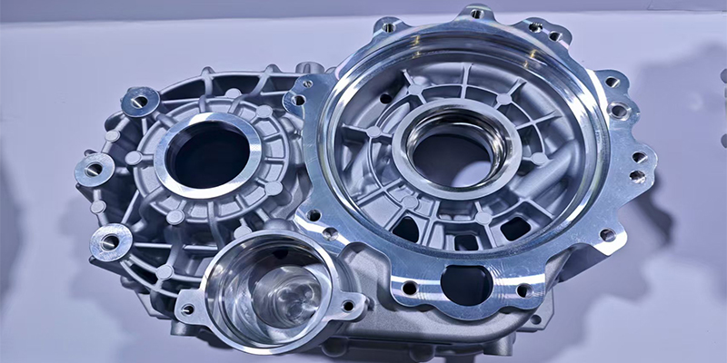 A diverse collage of high-pressure die-cast aluminum components from different industries: an automotive engine block part, an electronics housing, and a power tool casing.