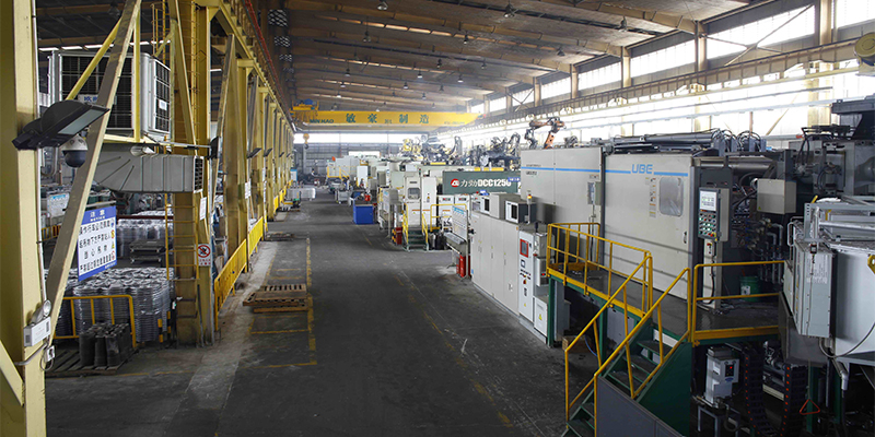 A factory floor scene showing multiple large HPDC machines in operation, producing various EV components, emphasizing high-volume manufacturing.